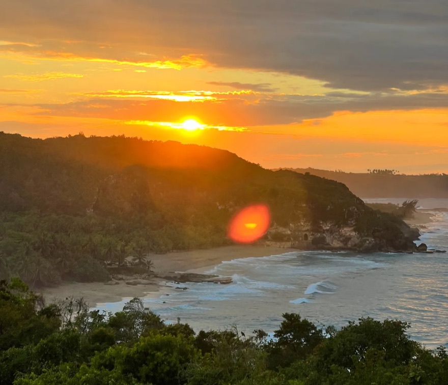 Sunset over a forested coastline and bay